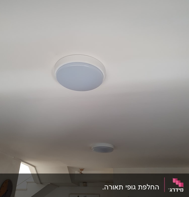 שני גופי תאורה עגולים מותקנים בתקרה לבנה